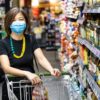 Asian woman shopping groceries in supermarket with protective face mask as new normal requirement