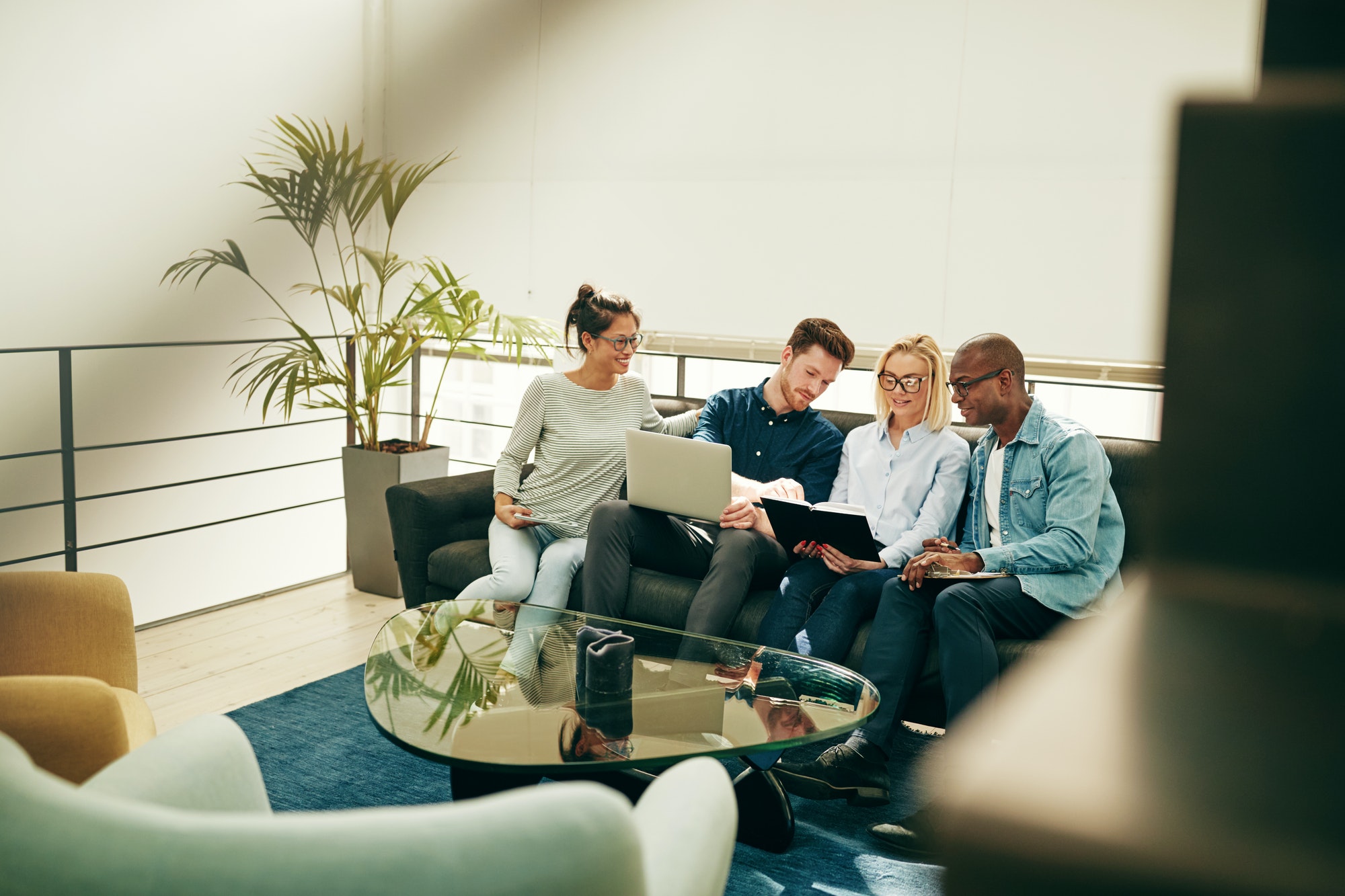 Group of young businesspeople sitting on a sofa discussing work