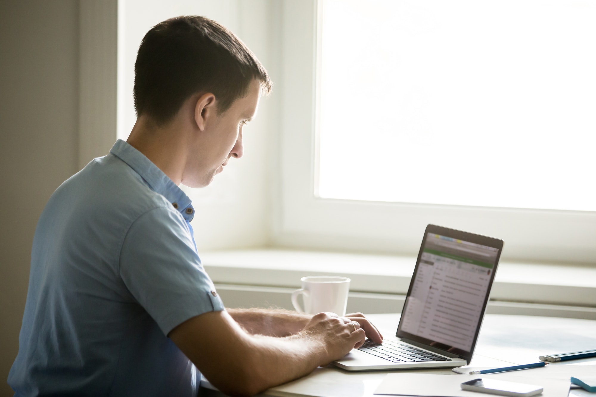 Profile portrait of young man working at desk with laptop