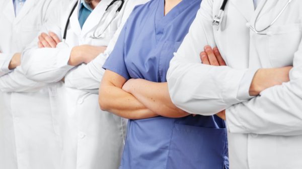 Doctors and nurses in healthcare team with arms crossed in a row in hospital