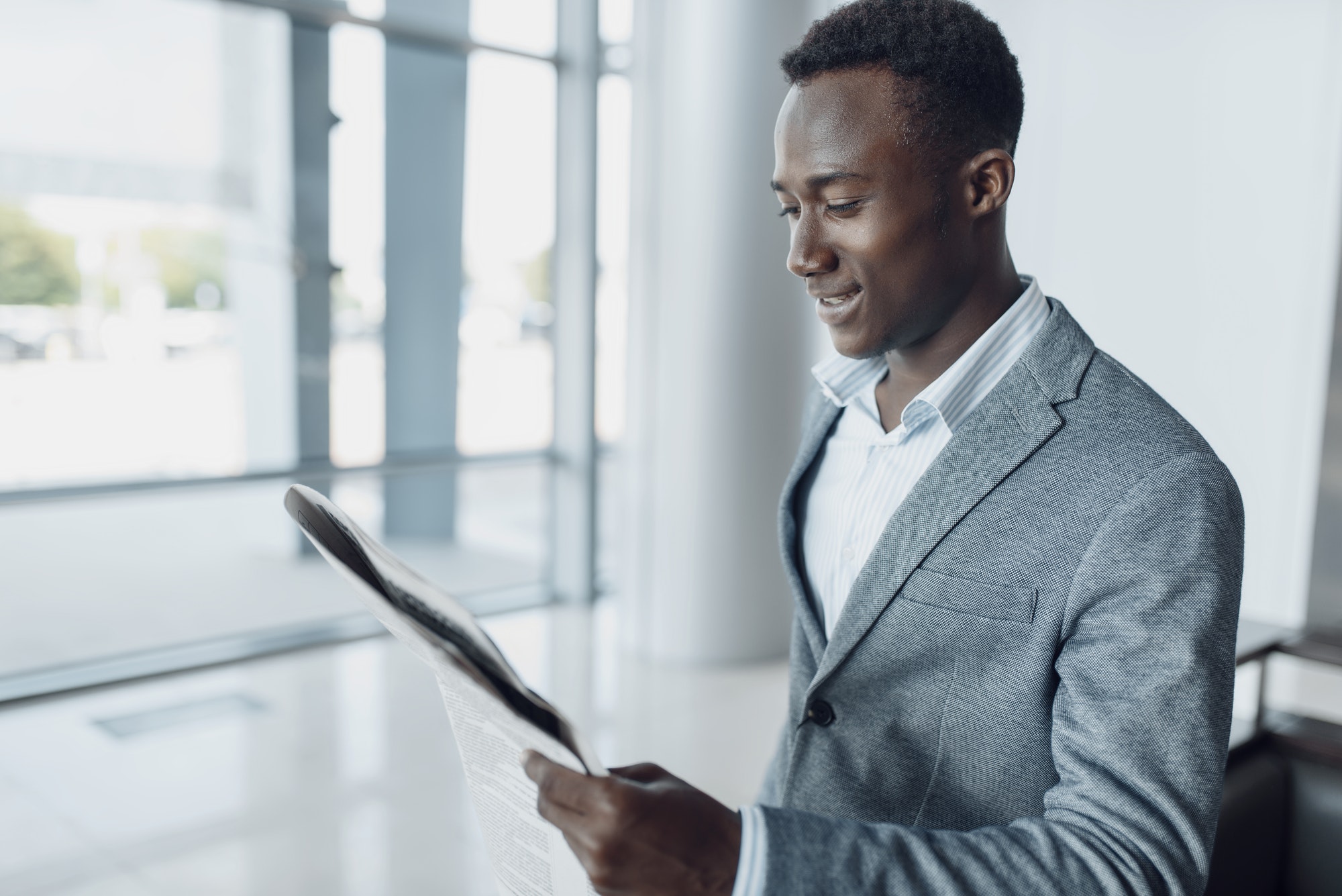 Black businessman with newspaper, office building