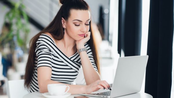 Bored woman surfing the internet in a cafe with a cup of coffee.