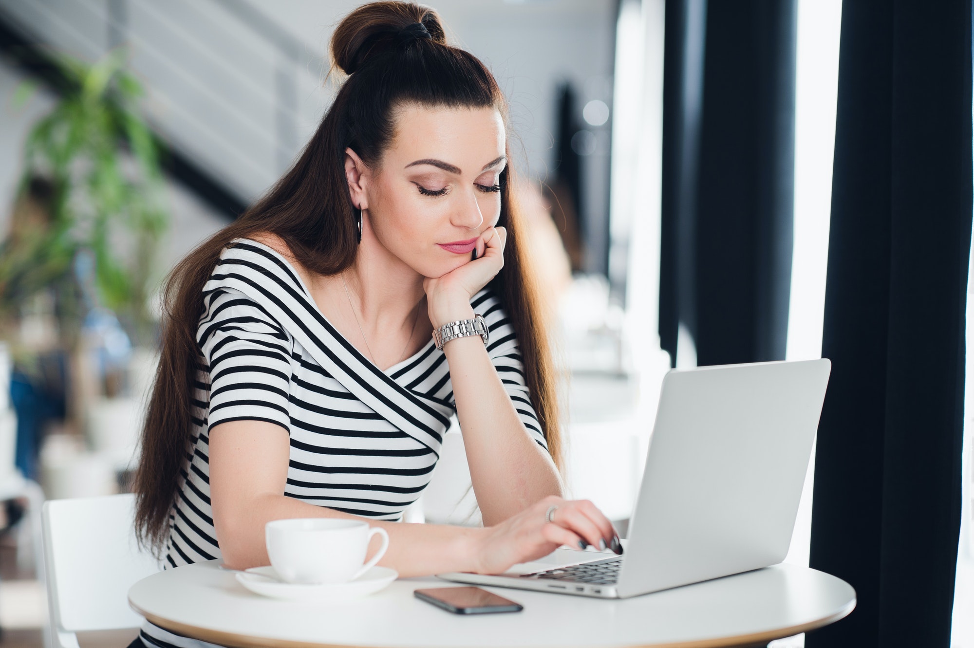 Bored woman surfing the internet in a cafe with a cup of coffee.