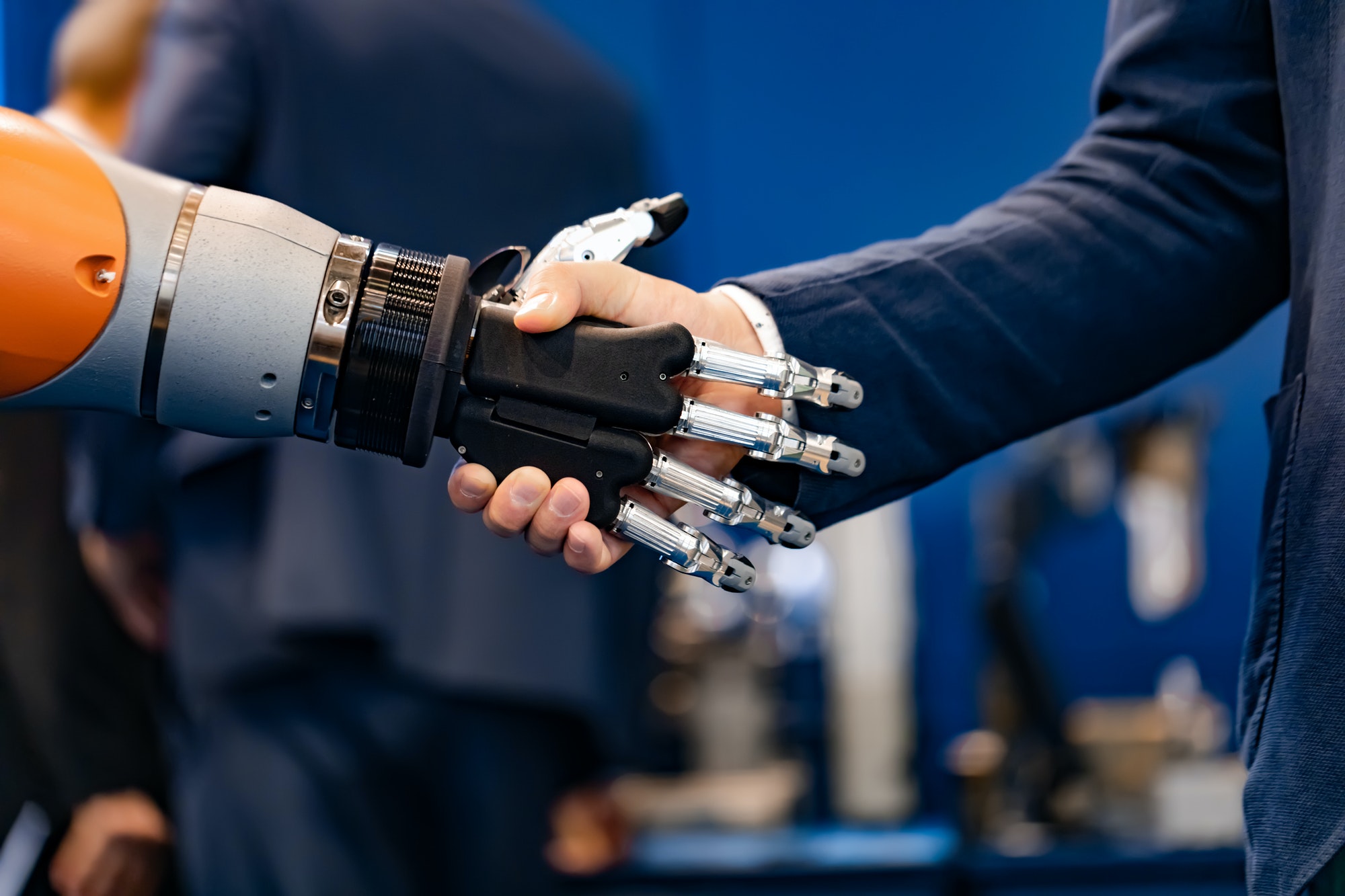 Hand of a businessman shaking hands with a Android robot.