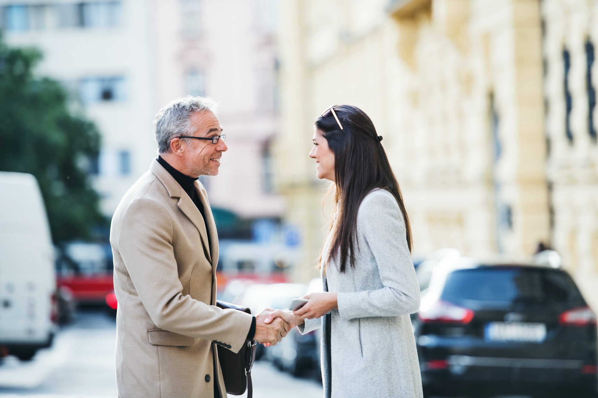 Man and woman business partners standing outdoors in city of Prague, shaking hands.